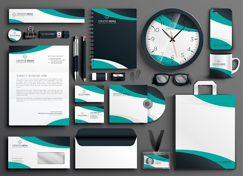 Branded letter head, pen, pencil, flash, business card, clock, bag, mug and phone case arranged on grey desk.